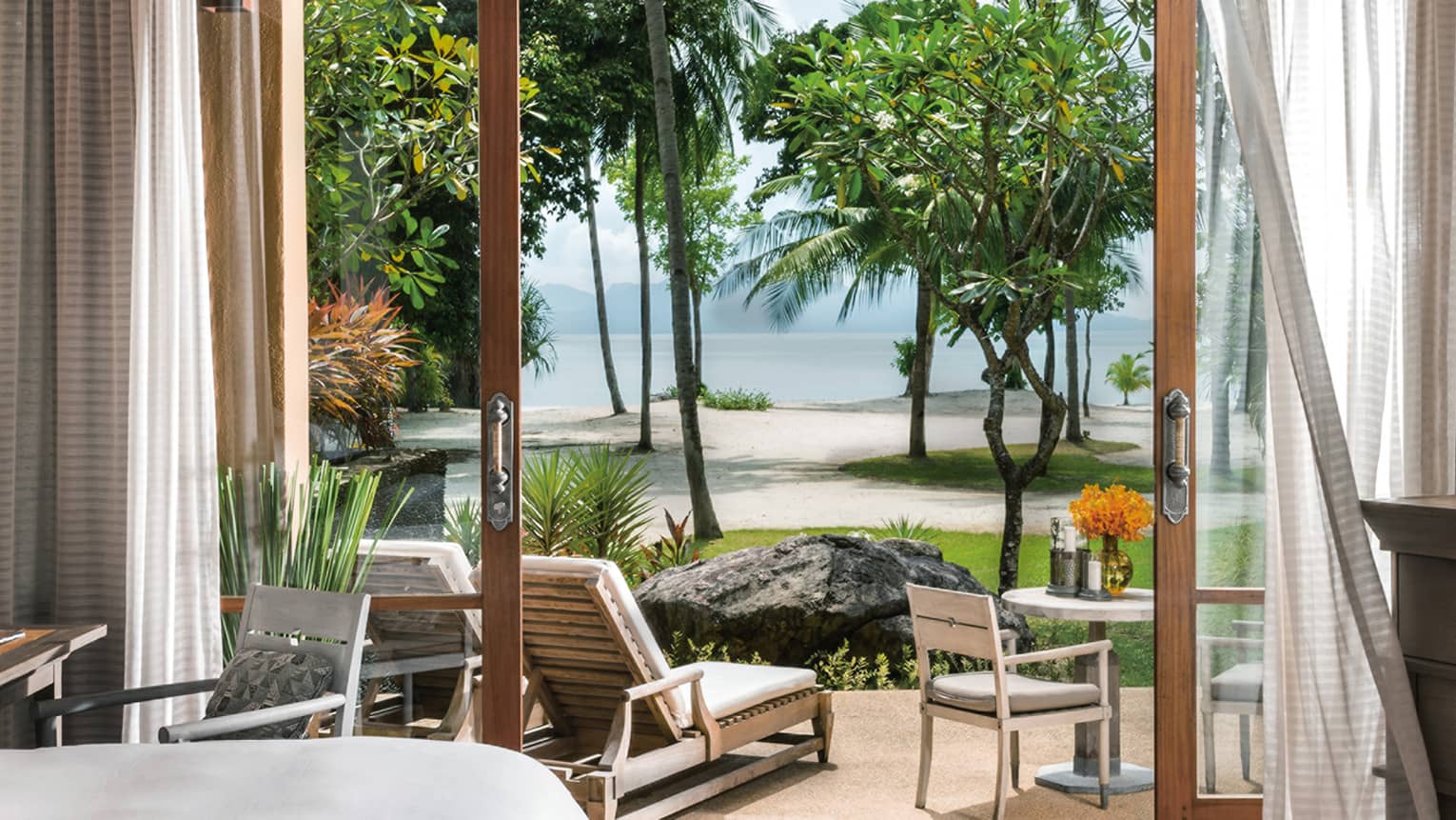 Curtains by open doors to ground floor pavillion, lounge chair by trees, beach views