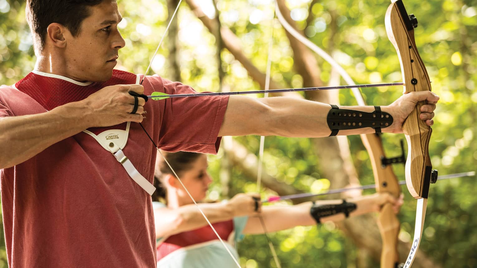 Man and woman hold bow and arrow, prepares to shoot