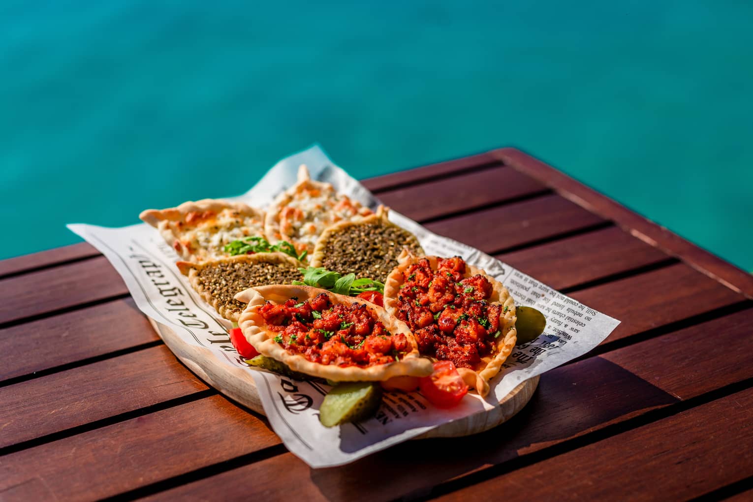 Manakish selection with levant pastry and various toppings on poolside table
