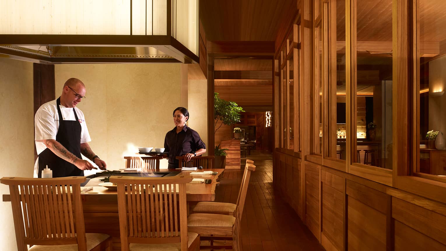 Chefs work at grill as flames leap out around him at small bar in NOBU restaurant