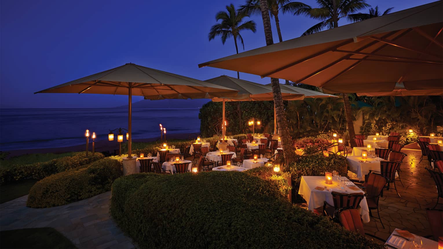 Ferraro's Bar e Ristorante at night, candle-lit dining tables with white tablecloths under patio umbrellas