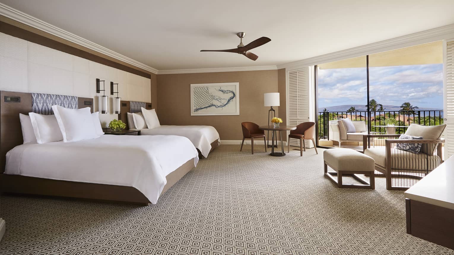 Luxury hotel room with two queen beds, sitting area and large balcony overlooking tropical scenery and ocean 