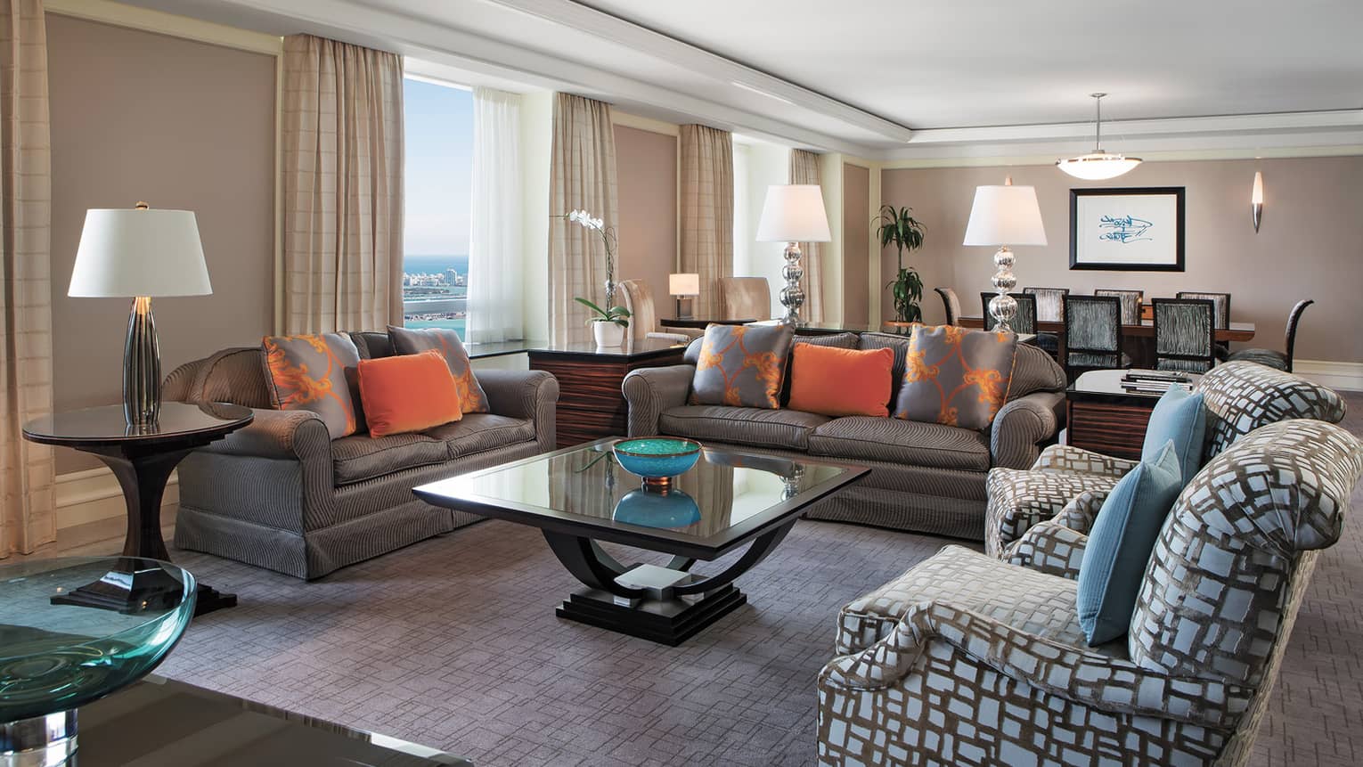 Living room with two sofas, glass square coffee table, two accent chairs, dining table