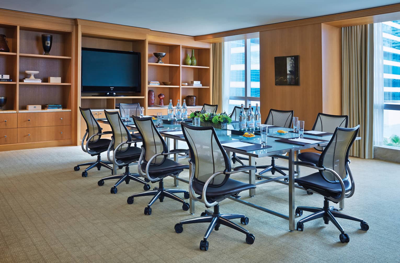 Swivel chairs line boardroom table in bright meeting room with shelves