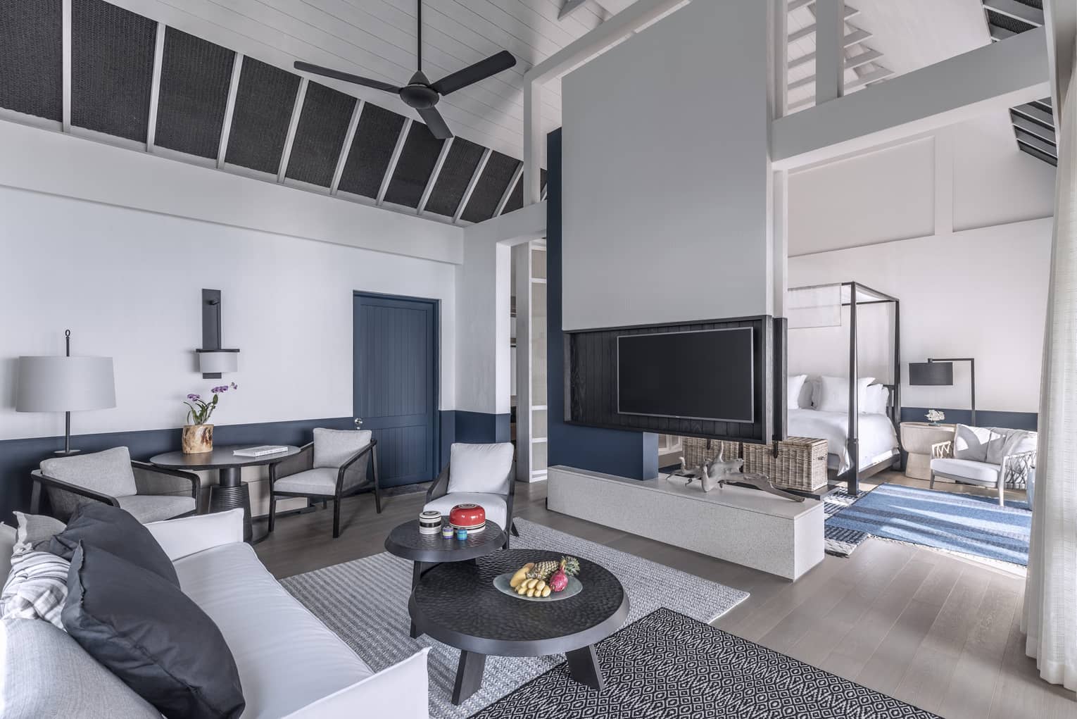 A brightly lit, cozy living room with a television, couch and access to the bedroom