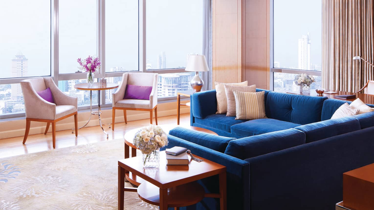 Deluxe Suite-Sea room with blue sectional sofa by floor-to-ceiling sunny windows, chairs