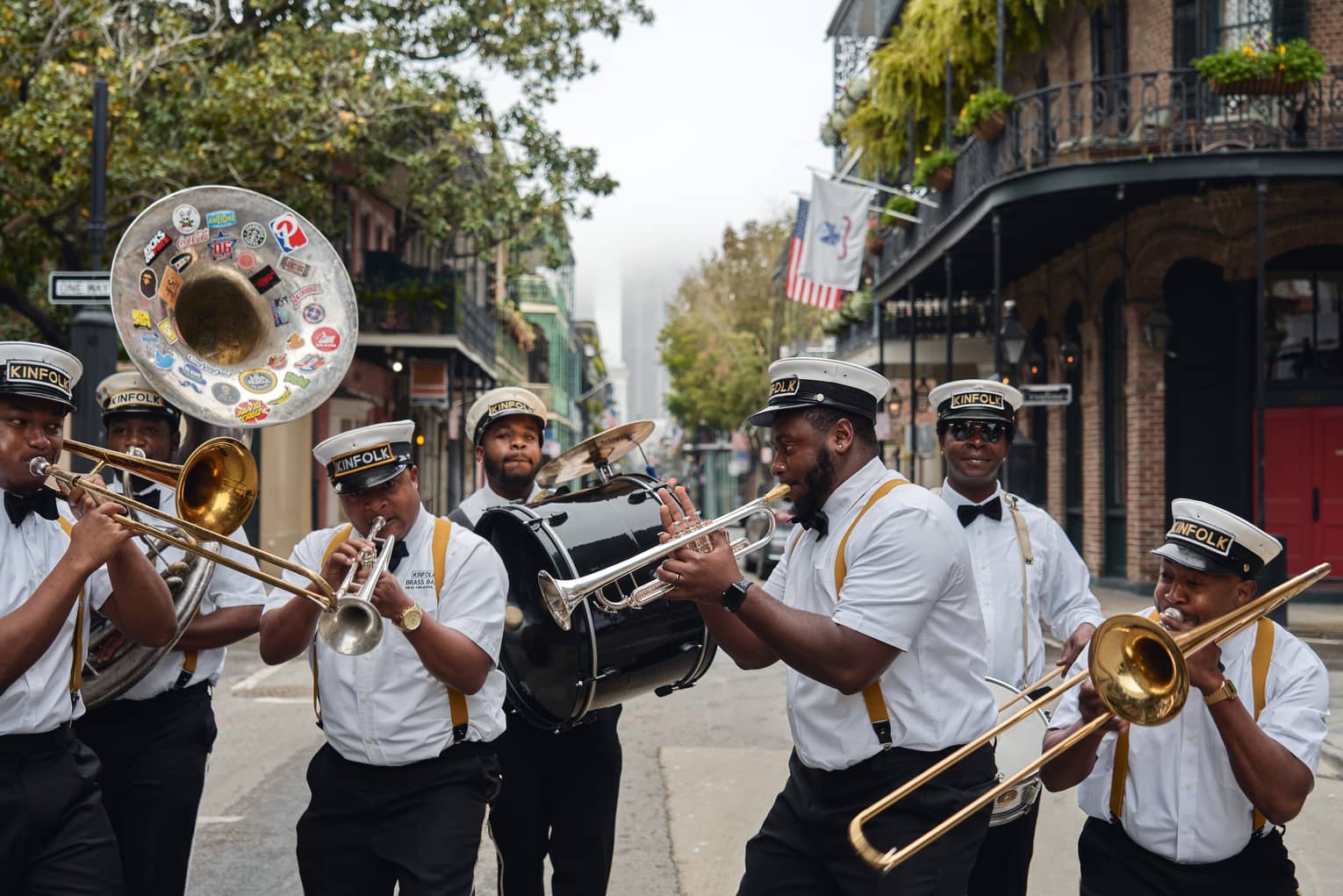 A group of men playing horned instruments while walking down a street.