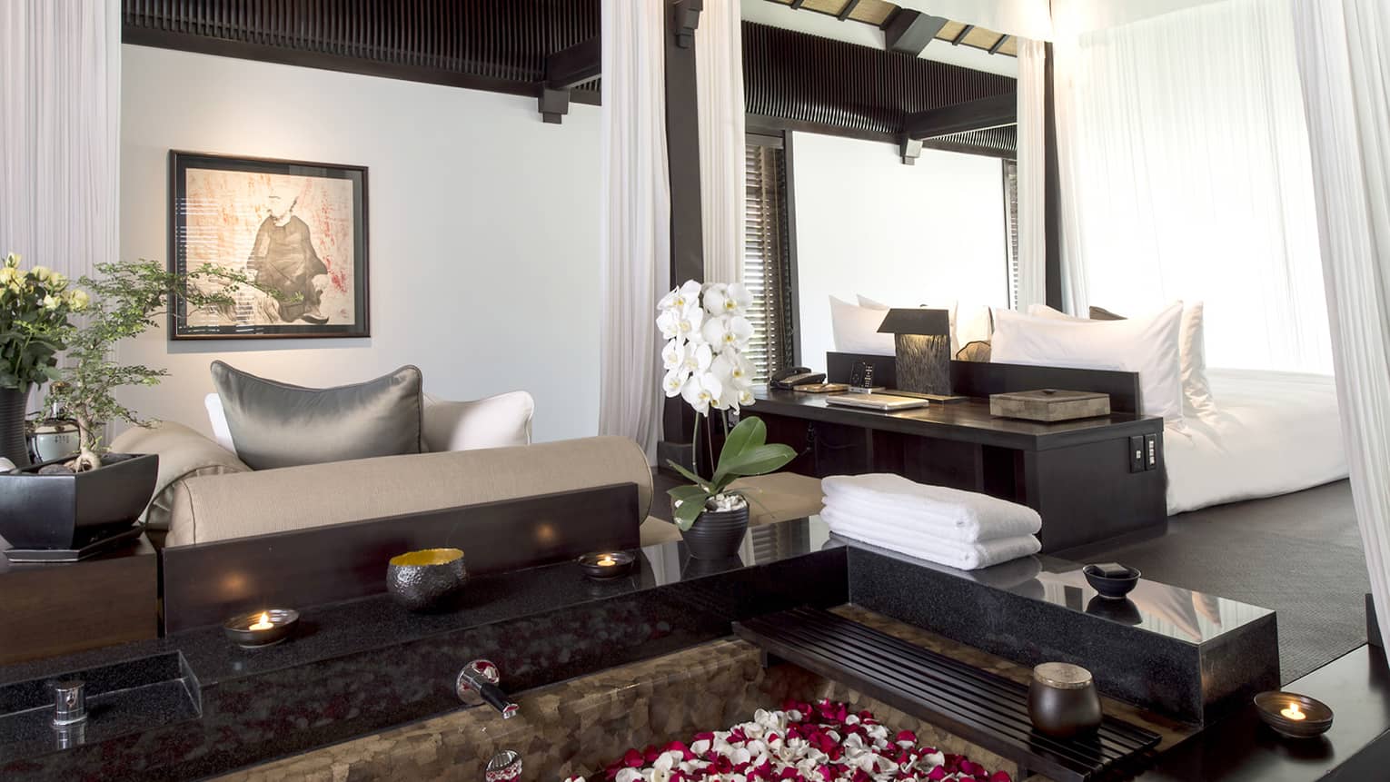 Pool Villa candle-lit tub filled with flower petals in middle of bright room, sofas