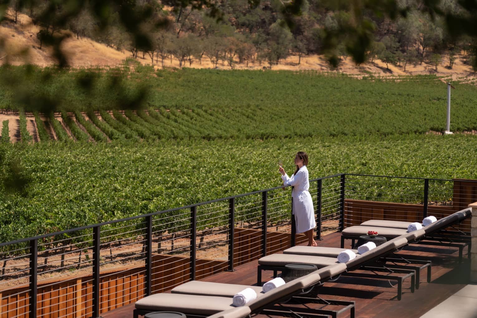 Person wearing a robe and holding a wine glass while admiring the views from the Spa sun deck.