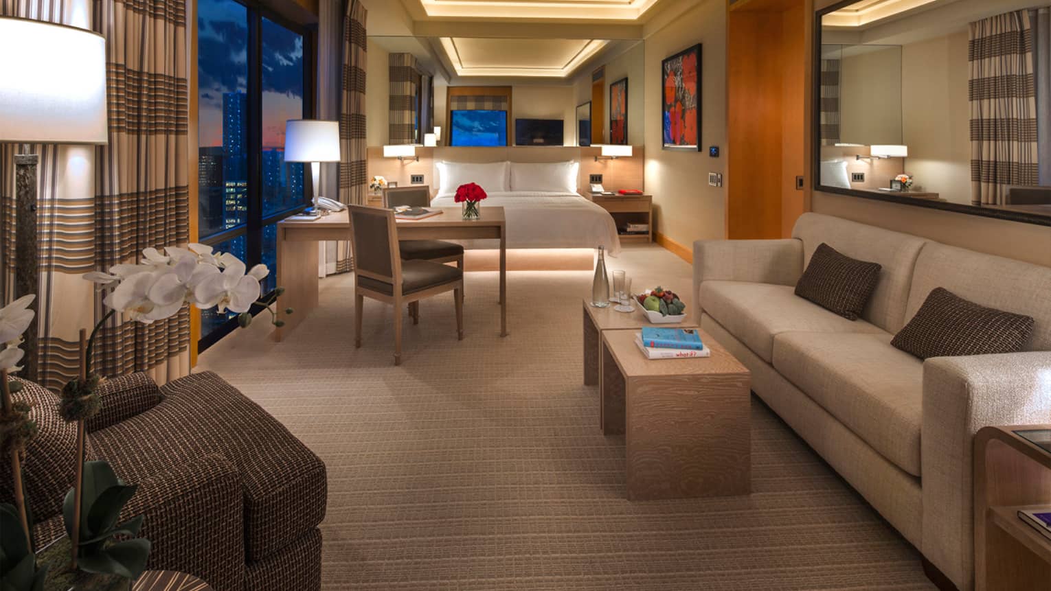 Gotham Suite at night with ceiling lights over bed, desk, sofa, reading chair