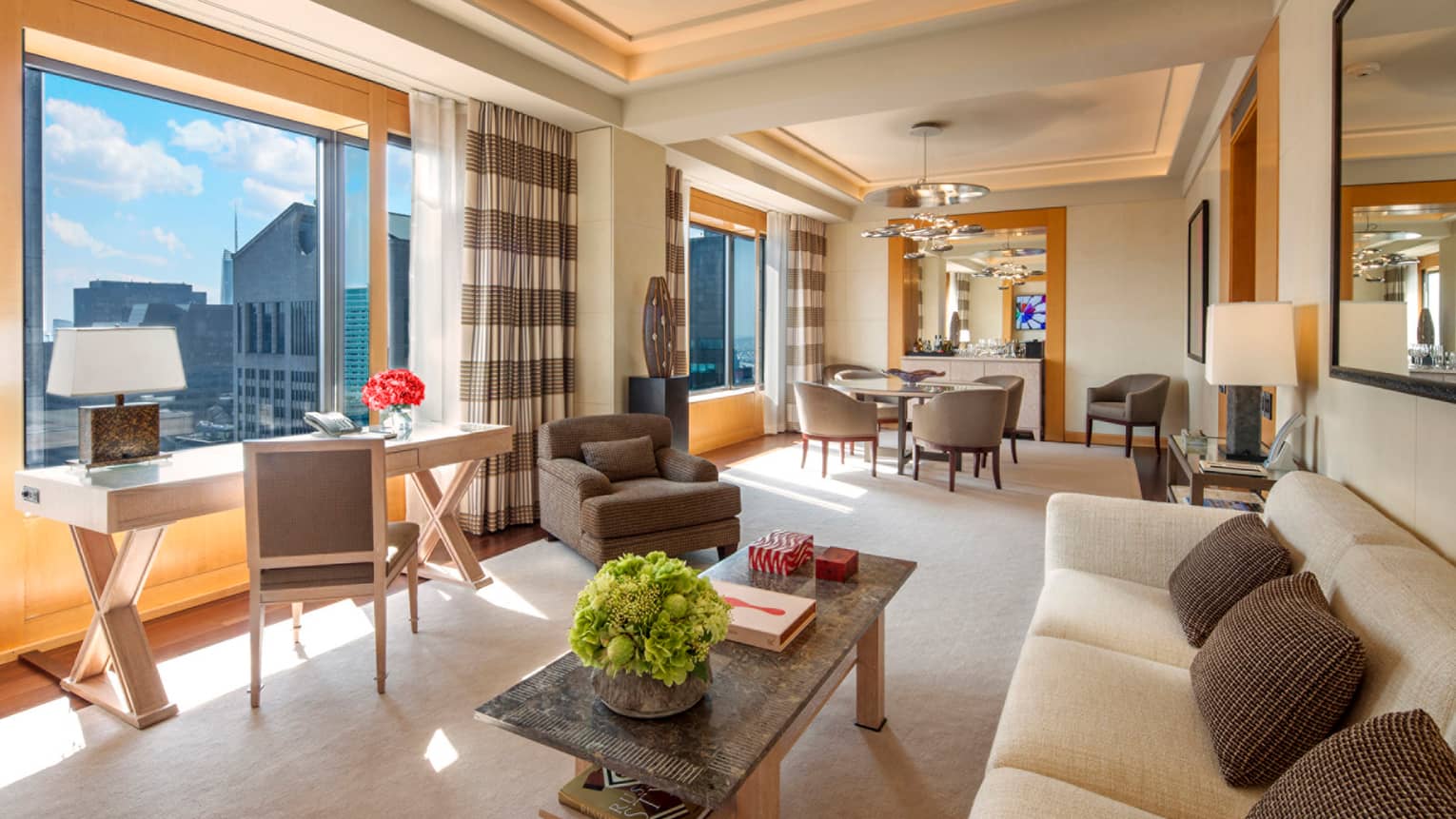 Manhattan Suite desk under sunny window, white sofa, dining table by bar