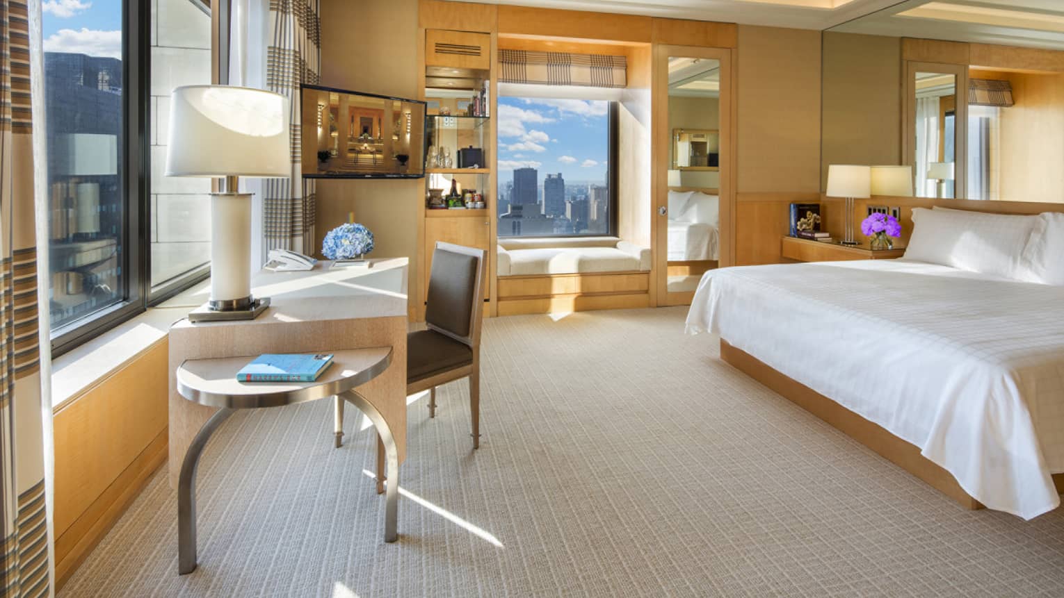 Studio 57 large corner room with bed, modern desk, chair and lamp by sunny window