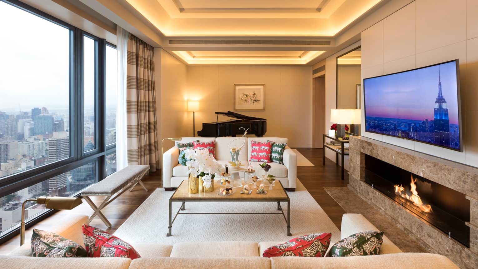Gotham Suite sofas, tables with trays of sweets between floor-to-ceiling window, large TV
