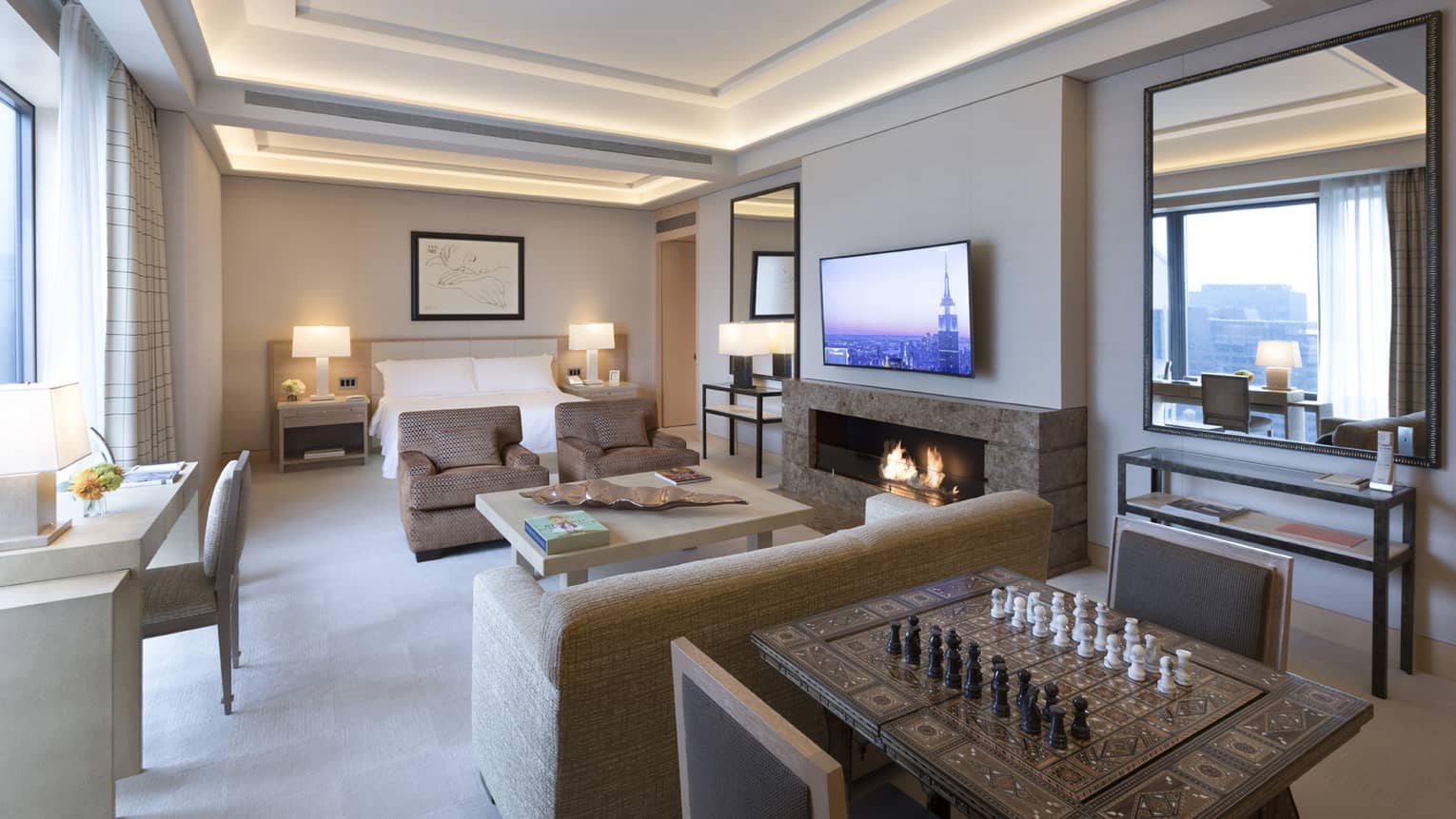 Gotham Suite table with chess board, seating area by fireplace and bed, desk at window