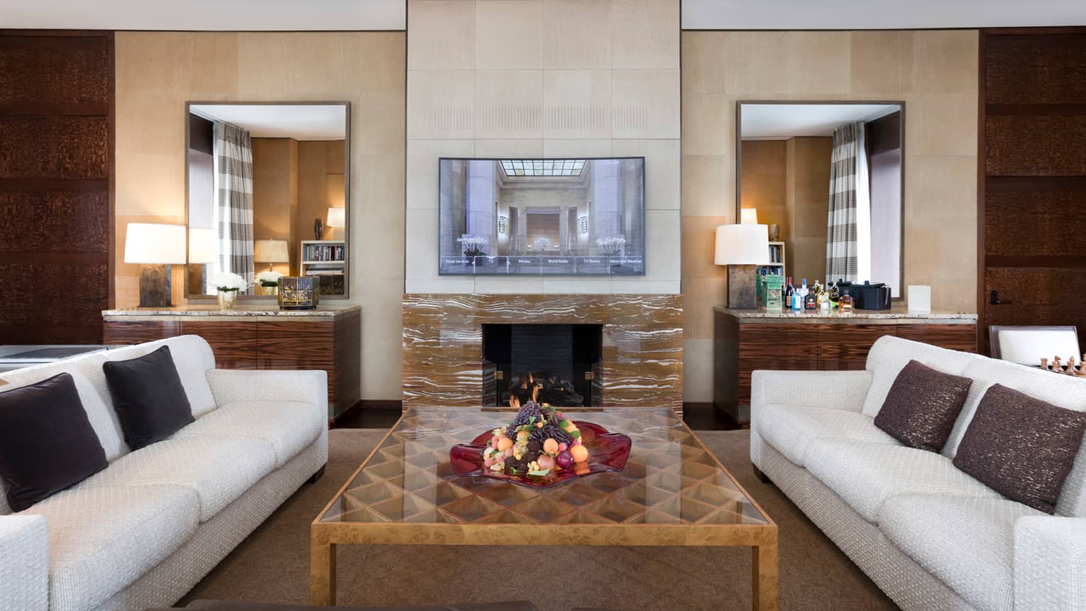 Presidential Suite white sofas around large table, wood-grain marble fireplace, TV on mantle