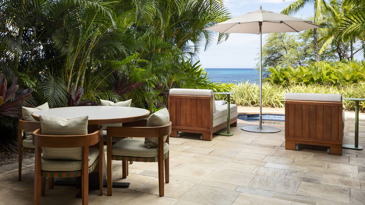 Private terrace with lush palm trees, dining table for four, two lounge chairs, spa tub and ocean view