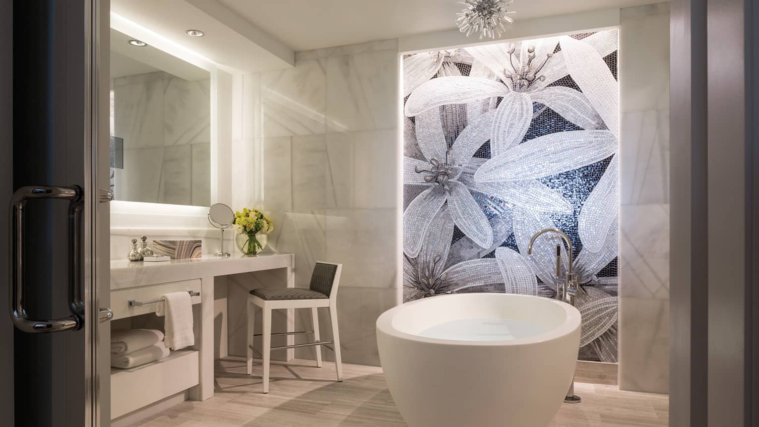 Grand Suite master bathroom white free-standing tub under mosaic tile wall with floral pattern, vanity