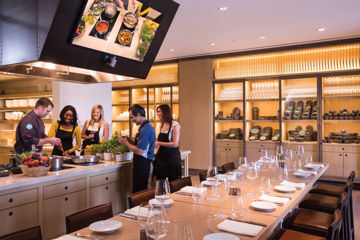 People wearing aprons gather around counter in Ravello Demonstration Kitchen 