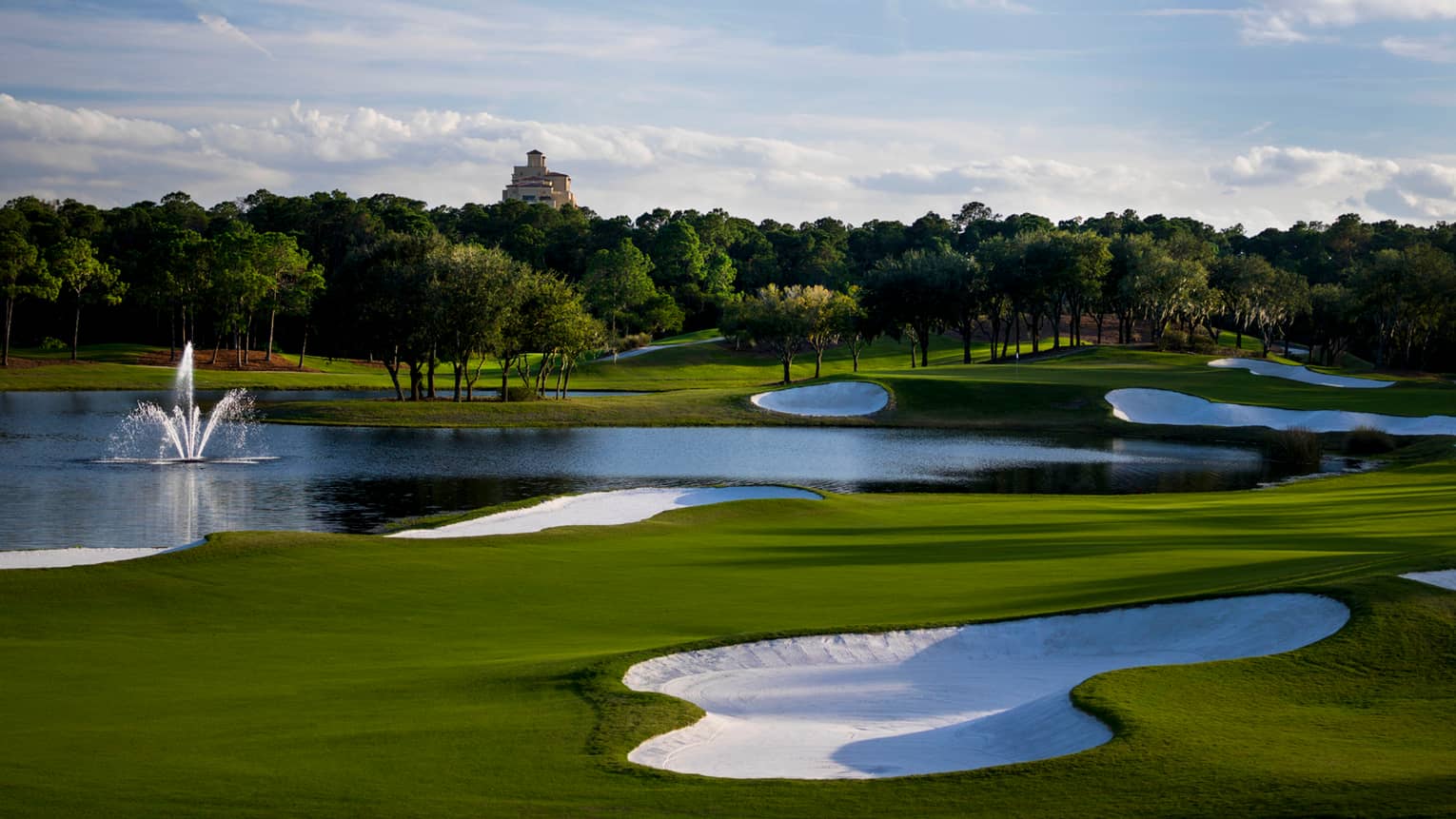 Golf course rolling green hills, sand bunkers, fountain in pond