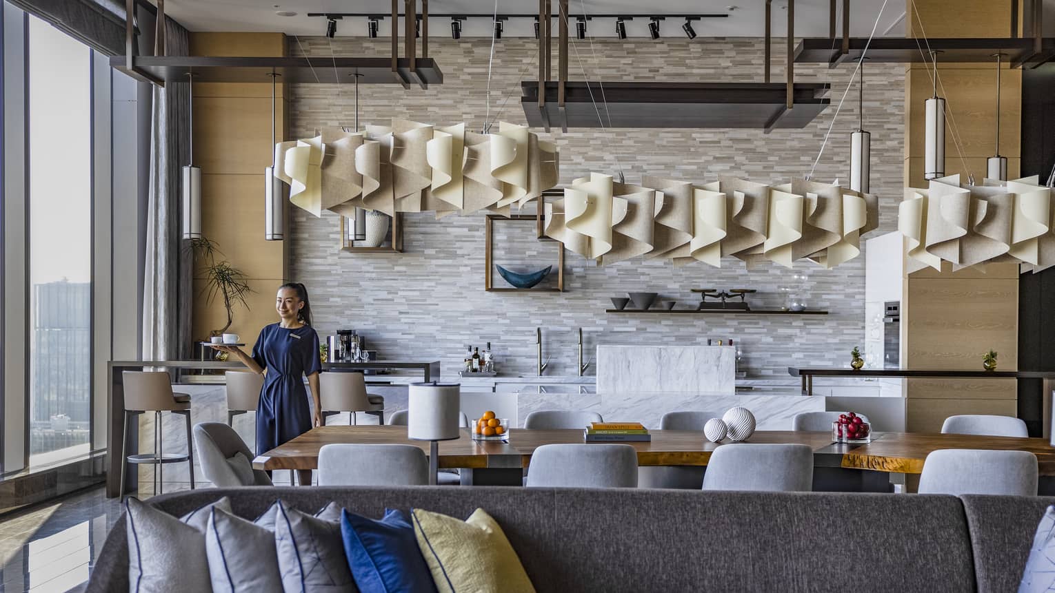 A smiling hotel staff member carries a tray of espresso to a guest out of frame