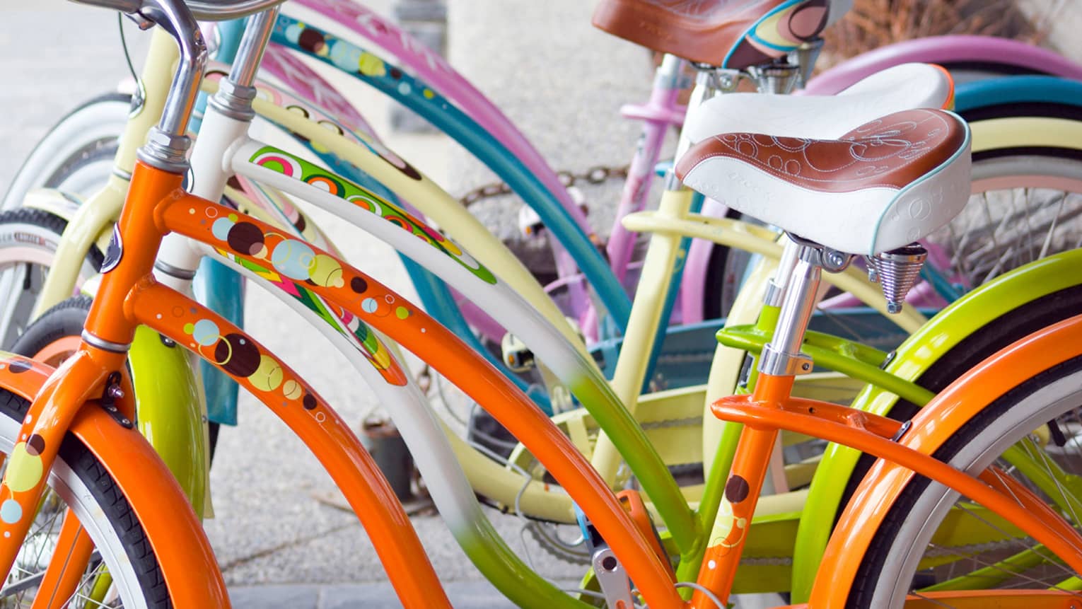Row of colourful bicycle frames in bright orange, green, yellow, blue and pink