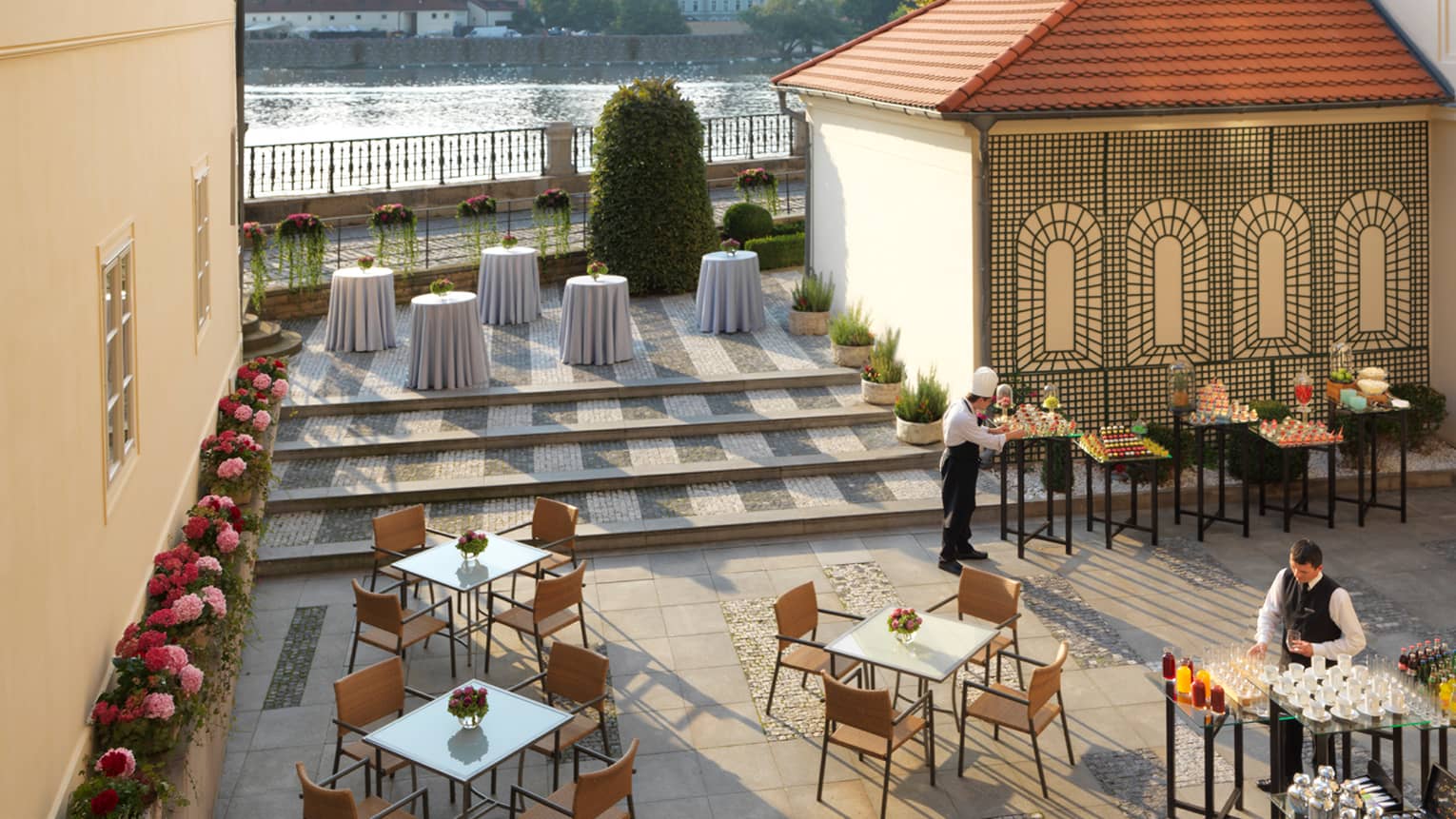 Aerial view of Karel Terrace patio tables and chairs, servers in uniforms prepare tables