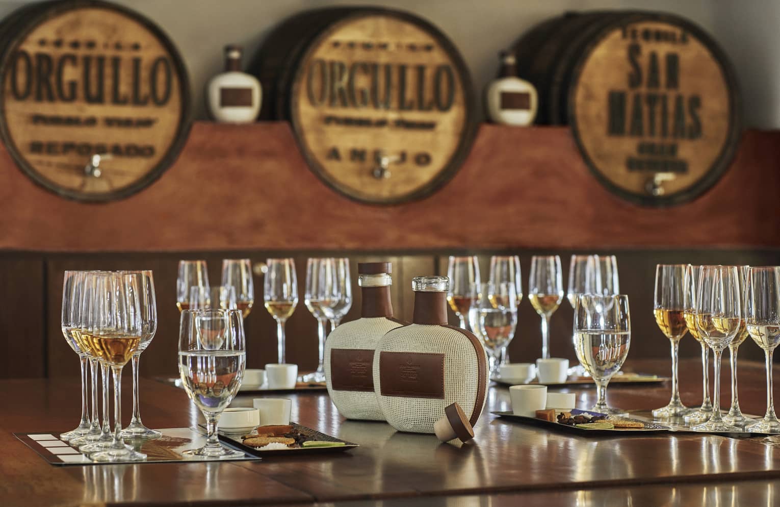 Tequila tasting, rows of wine glasses and cheese plates on table near tequila taps
