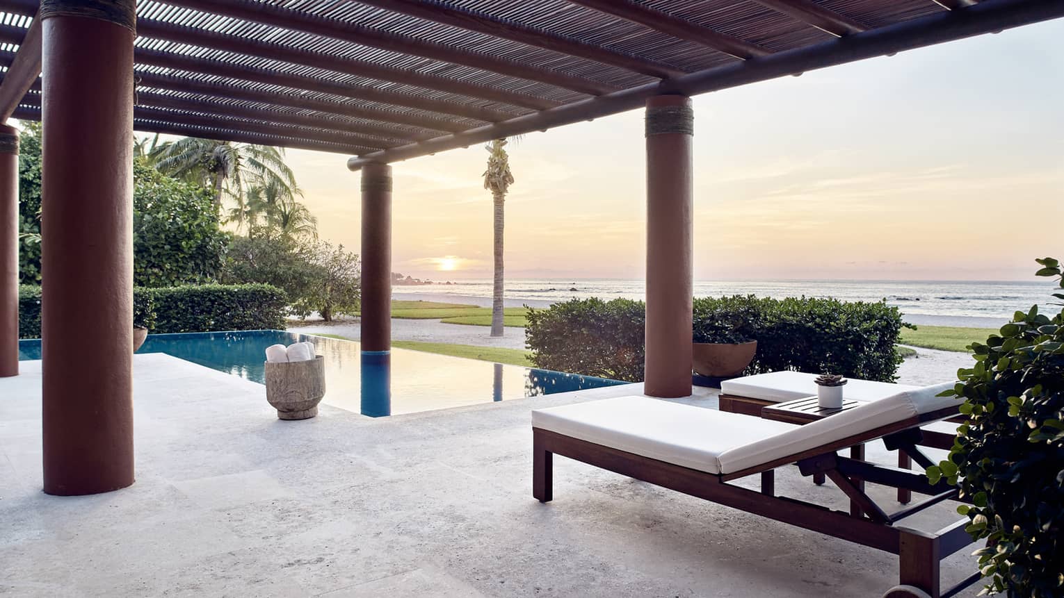 Outdoor terrace with lounge chairs, private pool, sun setting over the sea