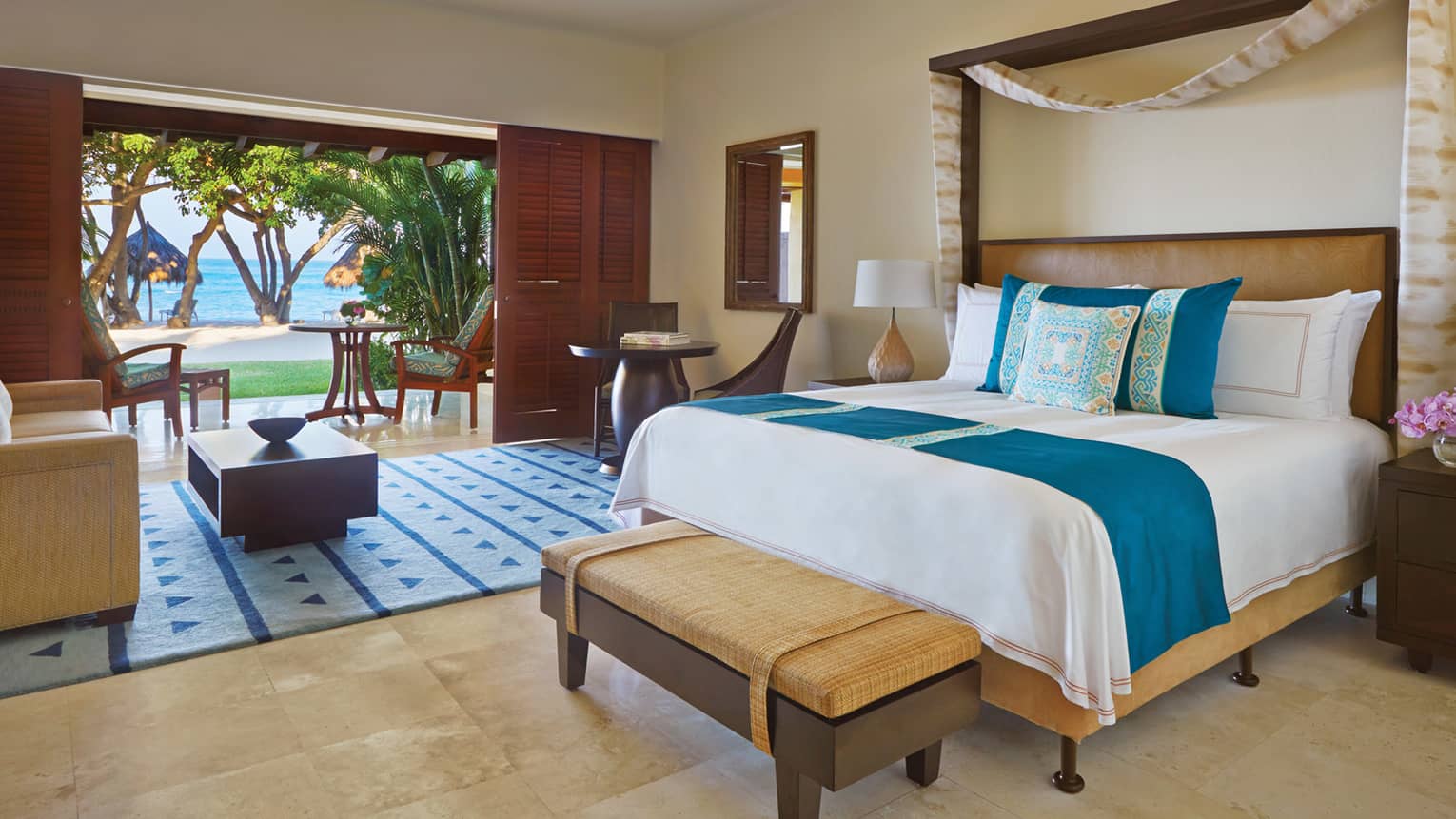 Casita beachfront room with bed, blue-and-yellow decorative pillow, living area, sliding wood doors to patio
