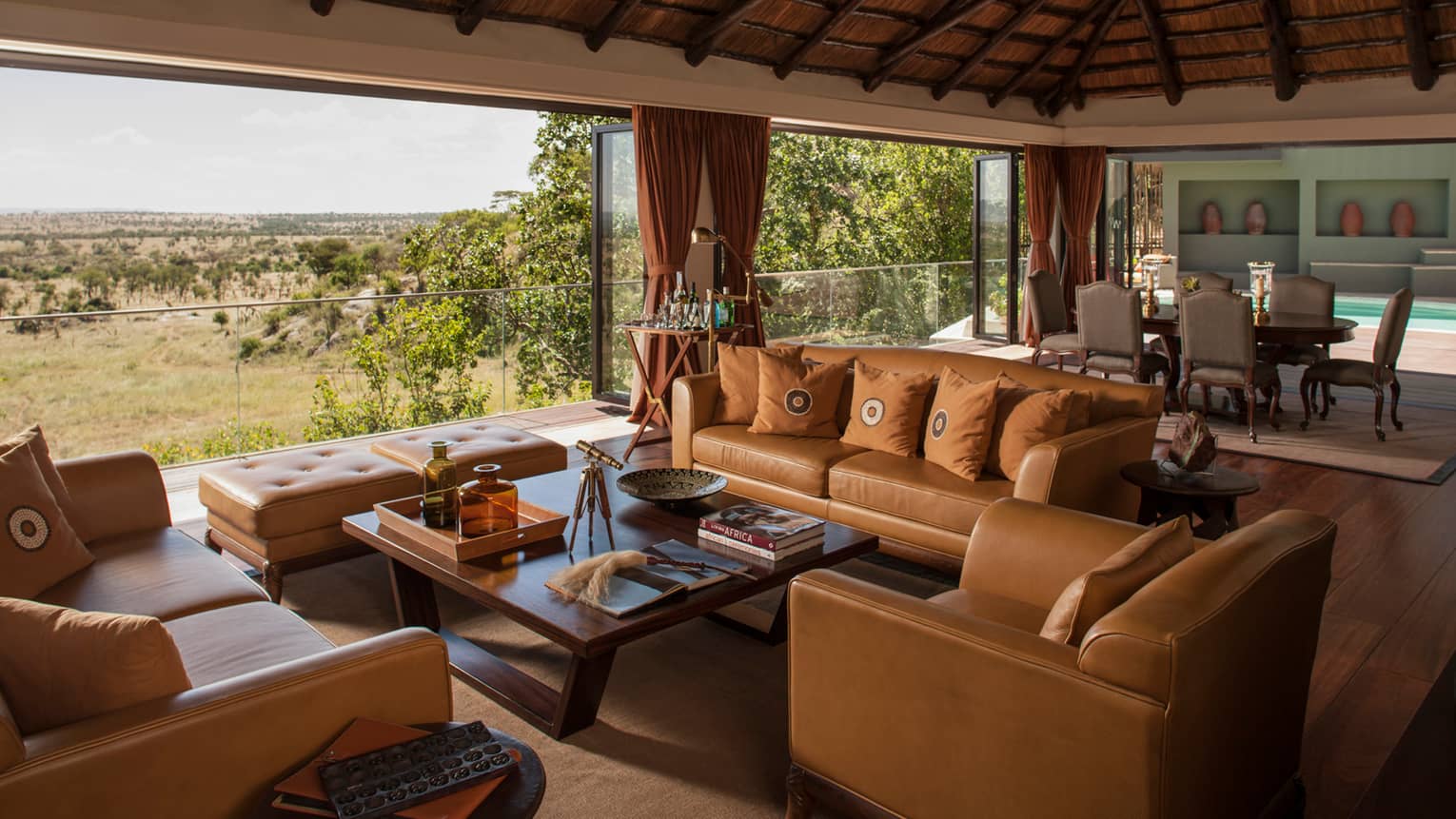 Presidential Villa tan leather sofas, chairs around table, large dining room, open wall