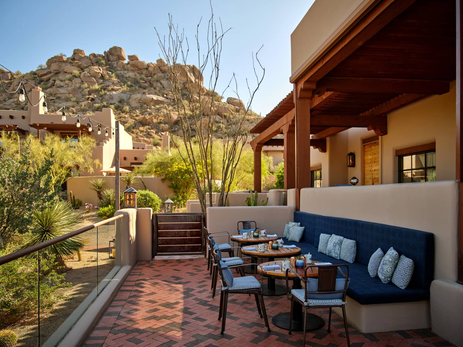 Outdoor terrace with booth seating and chairs and a view of the mountains.