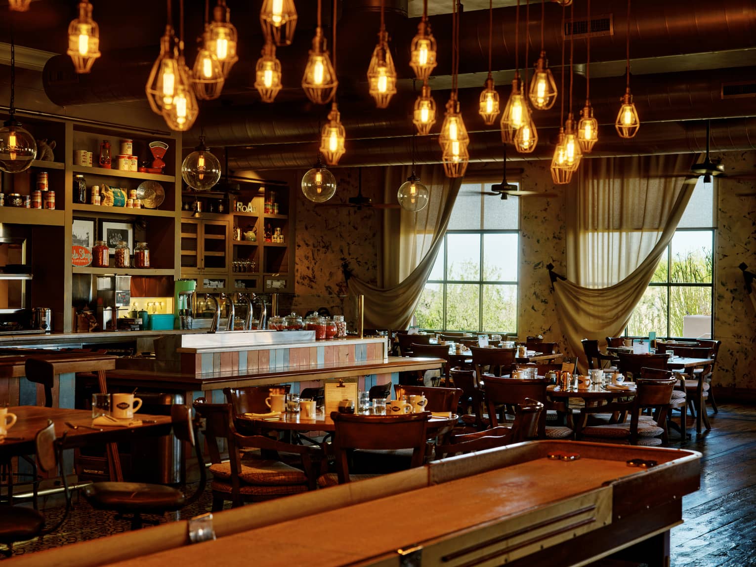Proof restaurant with shuffleboard table and hanging lights, at Four Seasons Resort Scottsdale