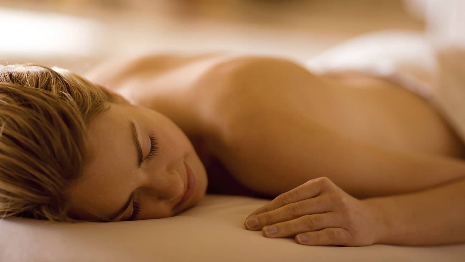 Woman lays with eyes closed, face-down on massage table