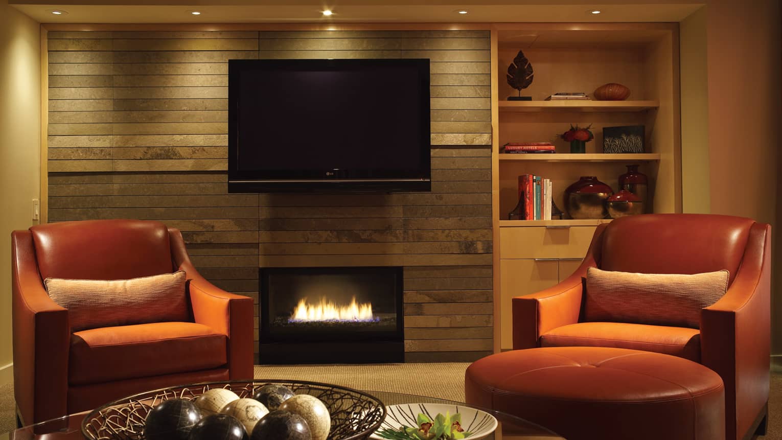 Red armchair beside gas fireplace, TV mounted on wall