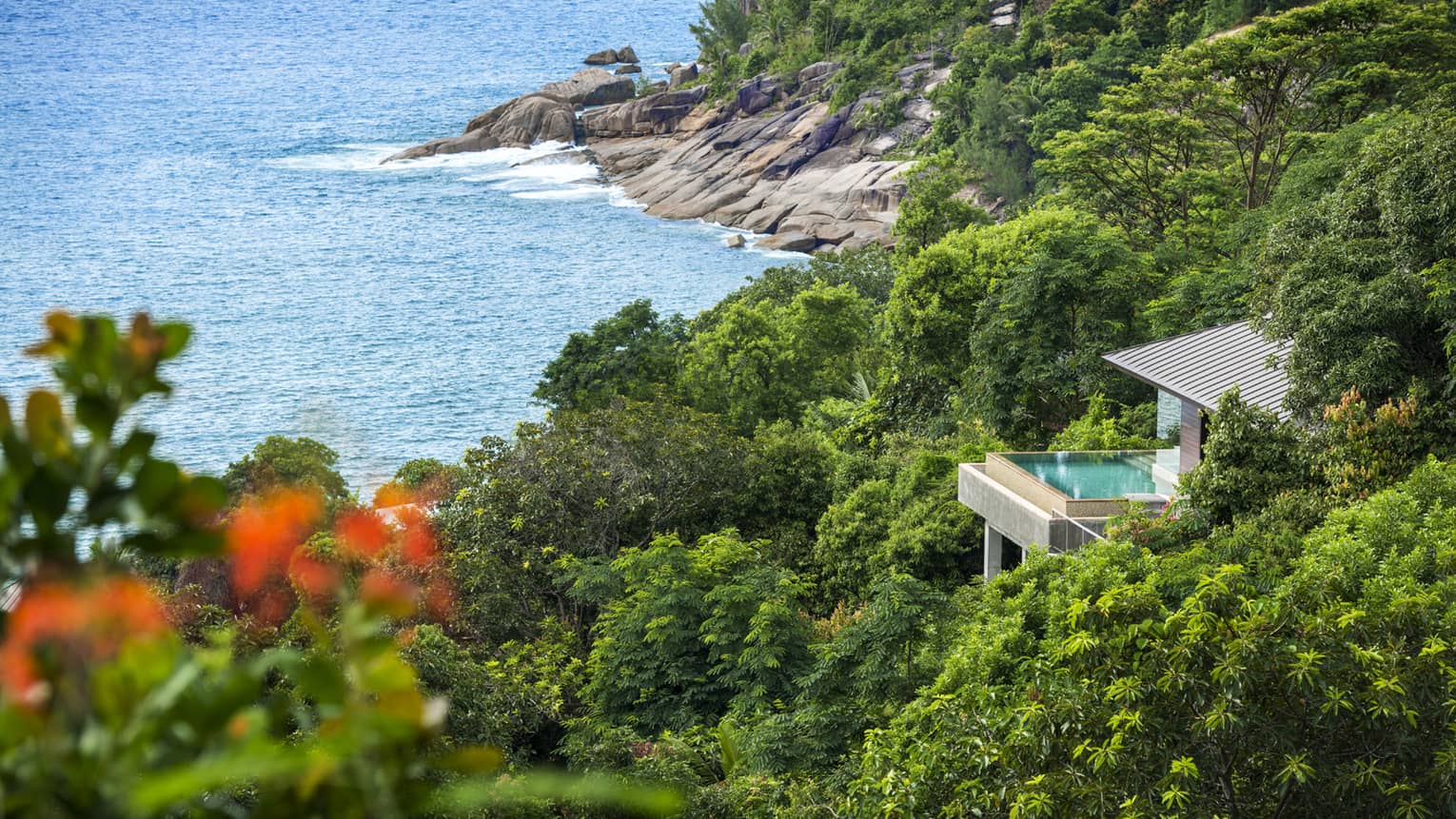 Overview of Villa nested among greenery, ocean and rocky shore below