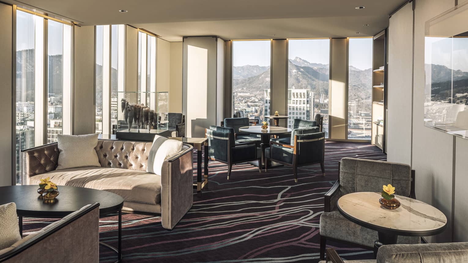 Lounge with tufted velvet sofas, cocktail tables and armchairs, floor-to-ceiling windows