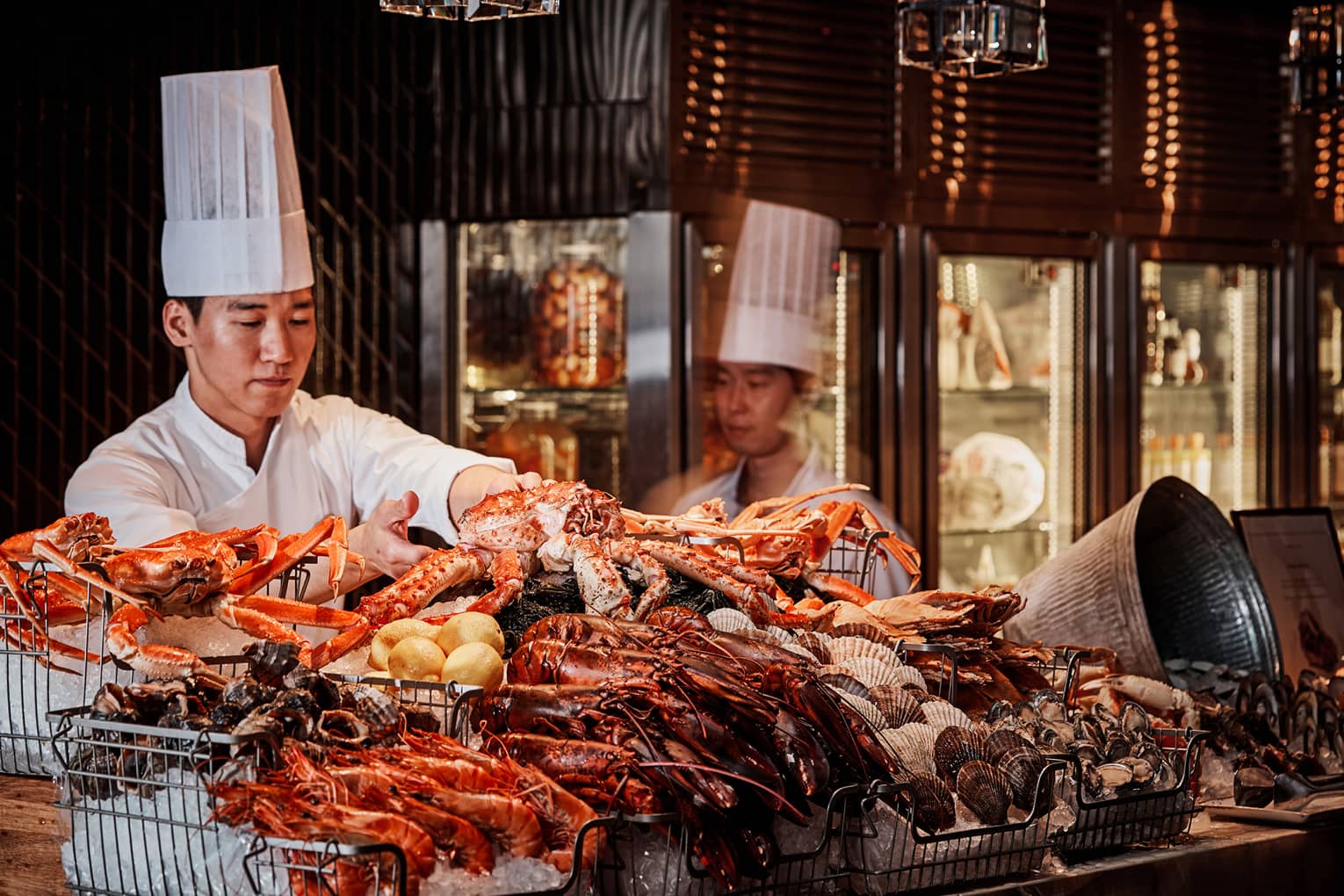 Chefs arrange large fresh crabs on ice at The Market Kitchen seafood buffet