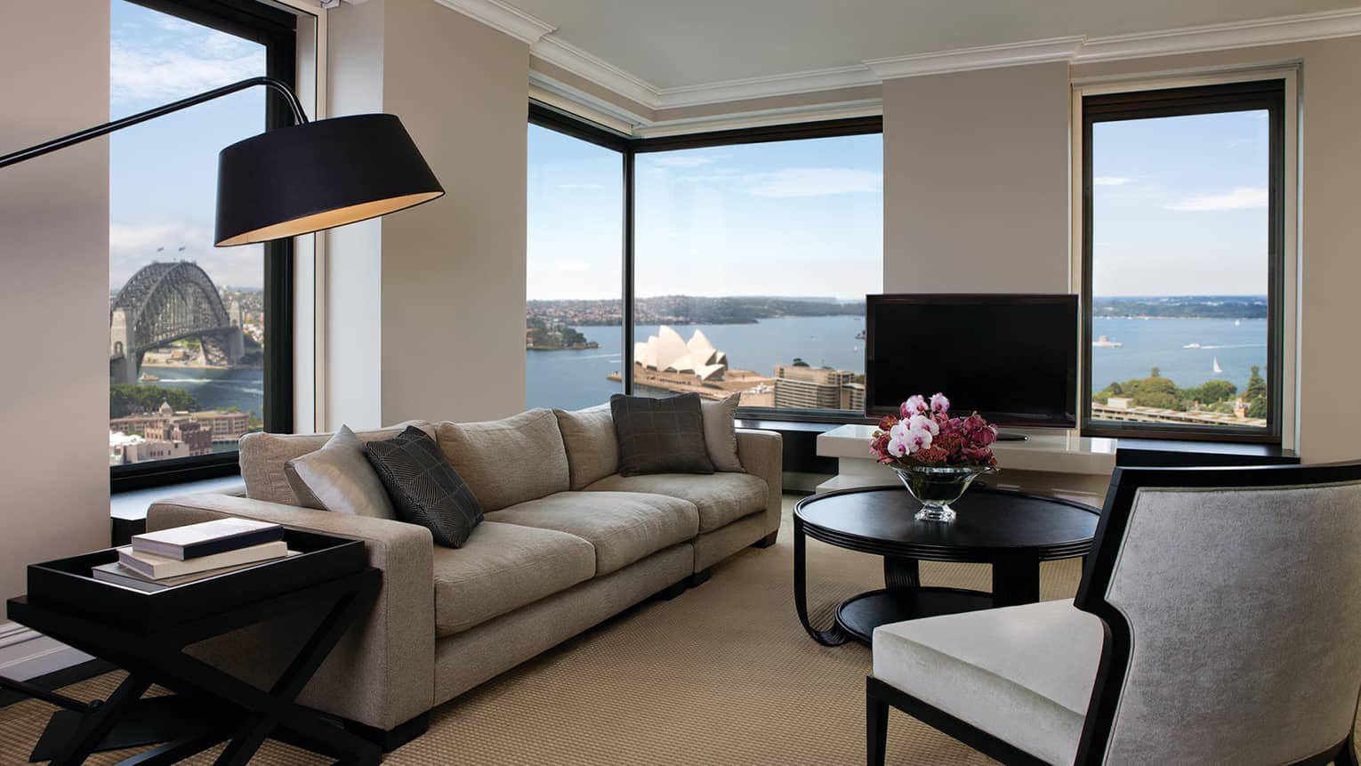Presidential Suite reading lamp over long plush sofa, armchairs, table by sunny corner windows