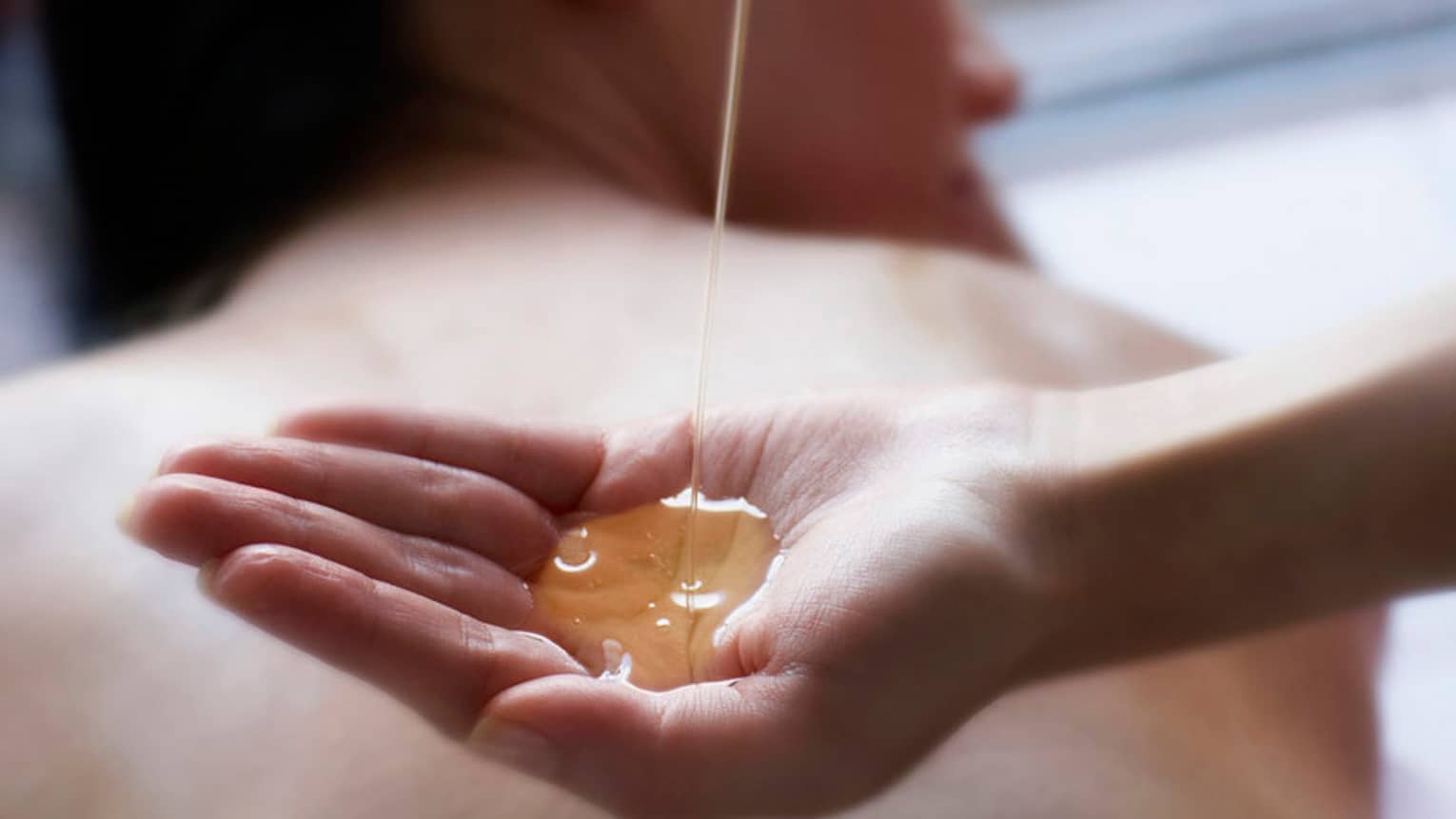 Stream of spa oil falls into open hand