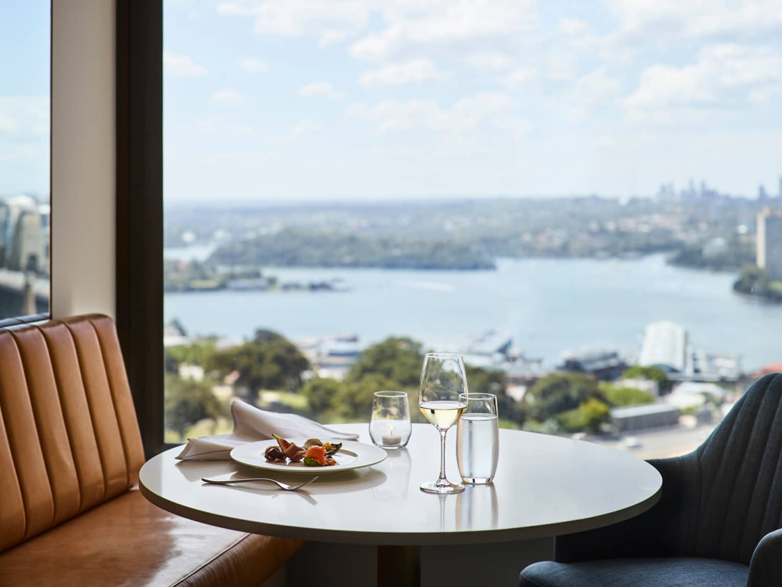 Lounge 32 meal, glass of white wine on round table by window with harbour views