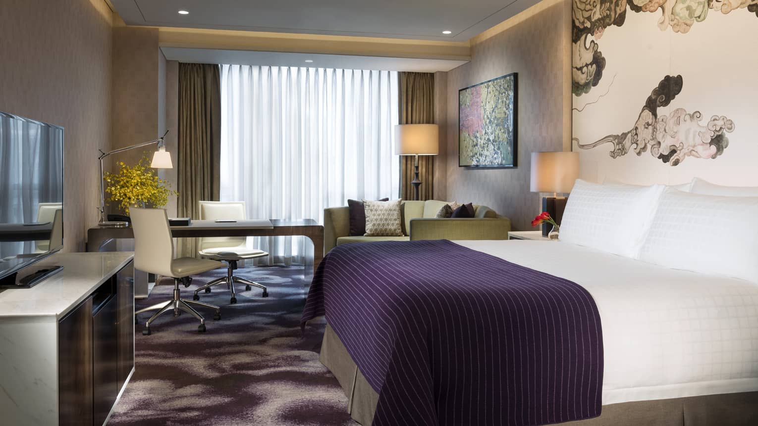 Premier Room hotel bed with indigo blanket, dresser and TV, desk by window