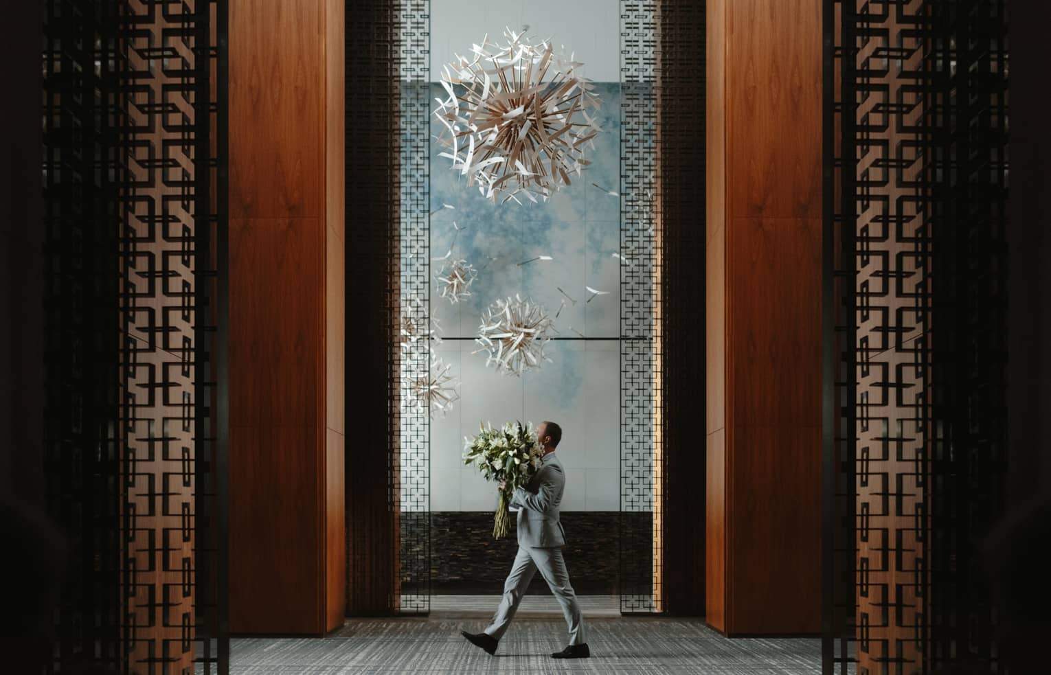 Man carries large floral arrangement through lobby of Four Seasons Hotel Toronto