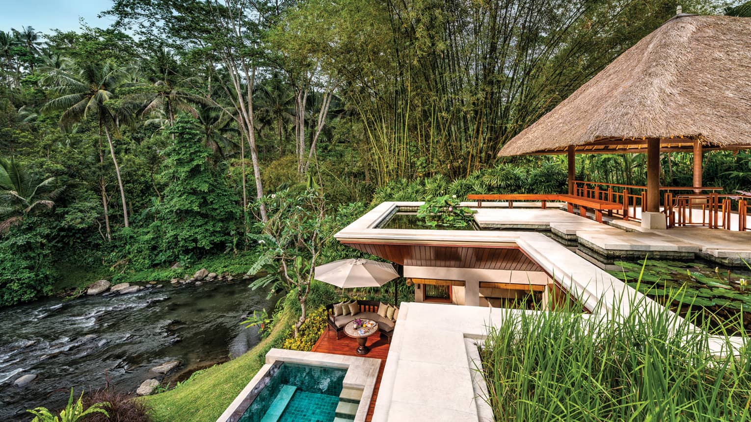 Looking down at multilevel resort patios with lotus pond on top, swimming pool and patio below, river beneath