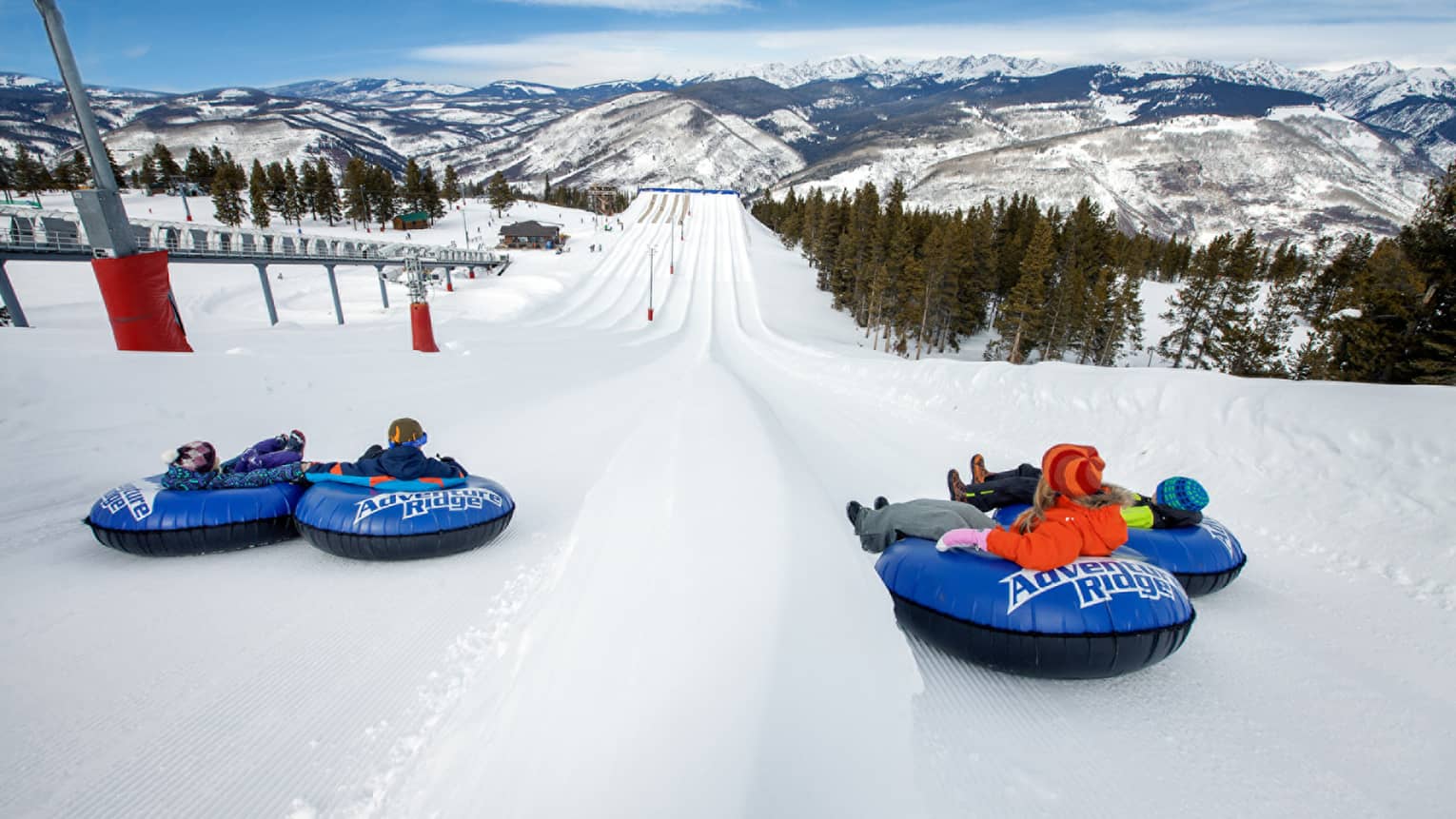 Four children on Adventure Ridge snow tubes at top of ski hill looking down