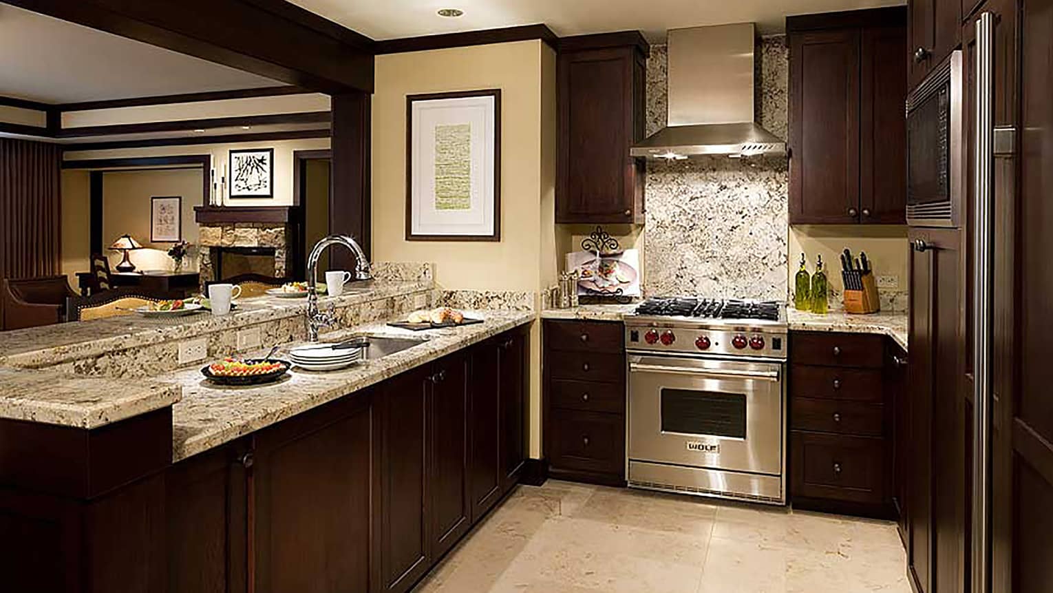 Kitchen with dark wood cupboards, marble counters, stainless steel stove