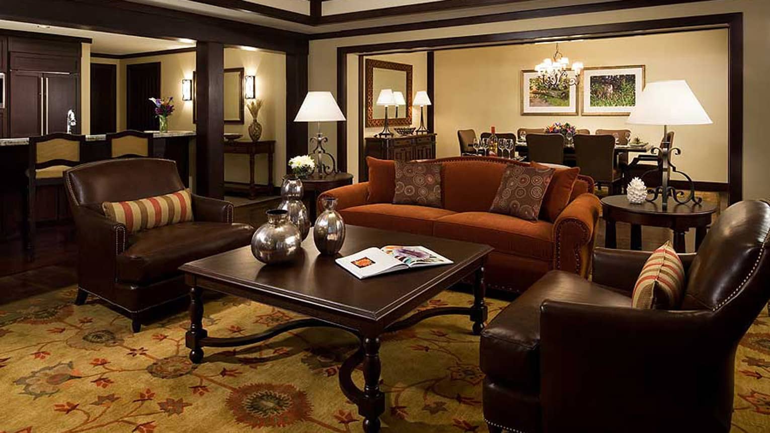 Two-bedroom with den residence suite living space with dark wood decor, private dining table, kitchenette 