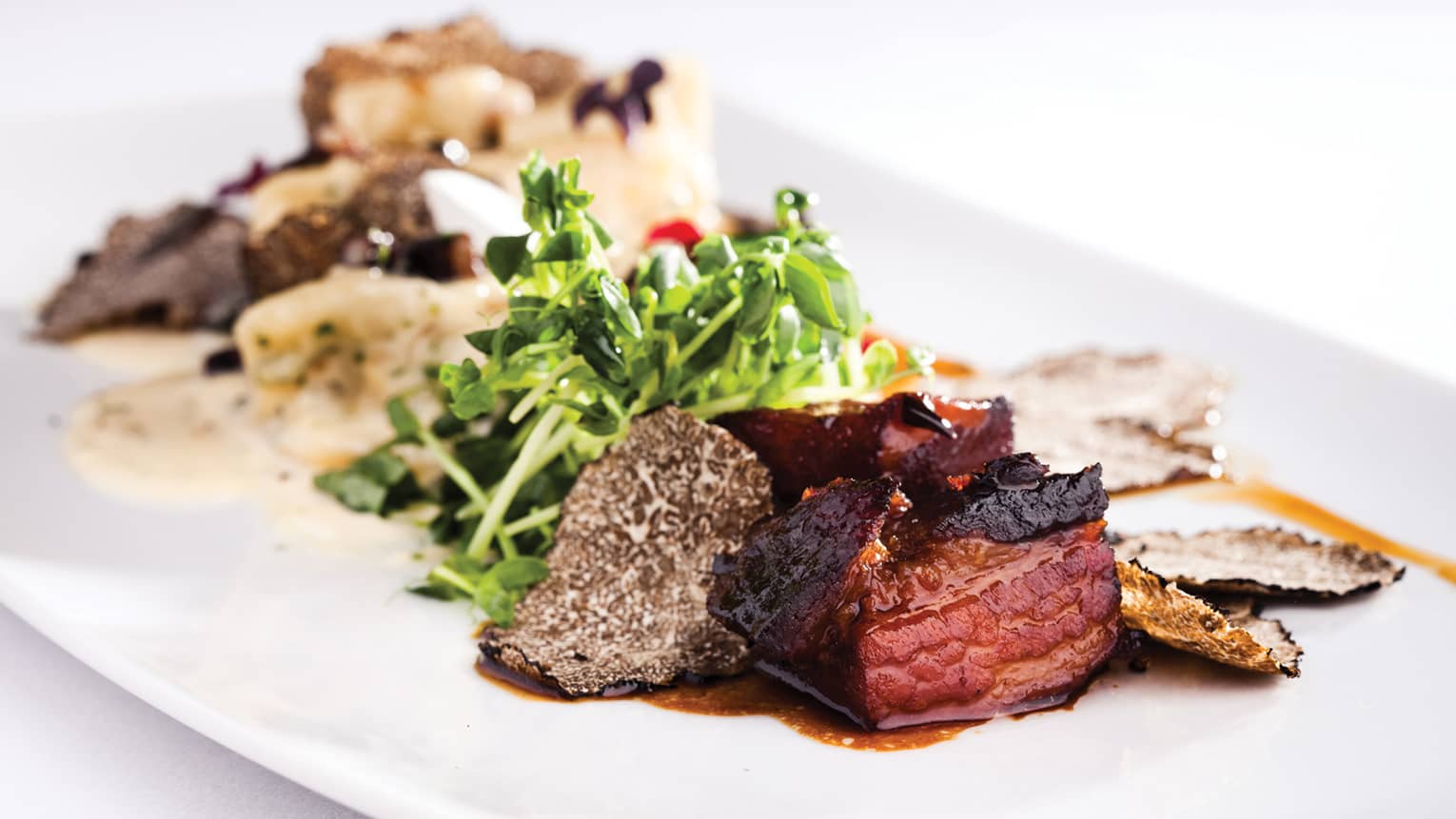 Close-up of juicy steak, mushroom, fresh greens on white platter