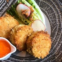 Three fried cakes, lettuce and radish rounds on plate