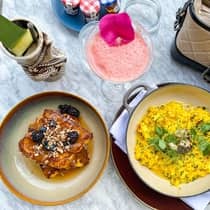 A pink cocktail and different pasta on a marble counter.