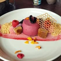 Vibrant blackberry mousse, honey sponge cake, elderflower honey, citrus streusel and raspberry whipped ganache with a decorative honeycomb and dried flower petals